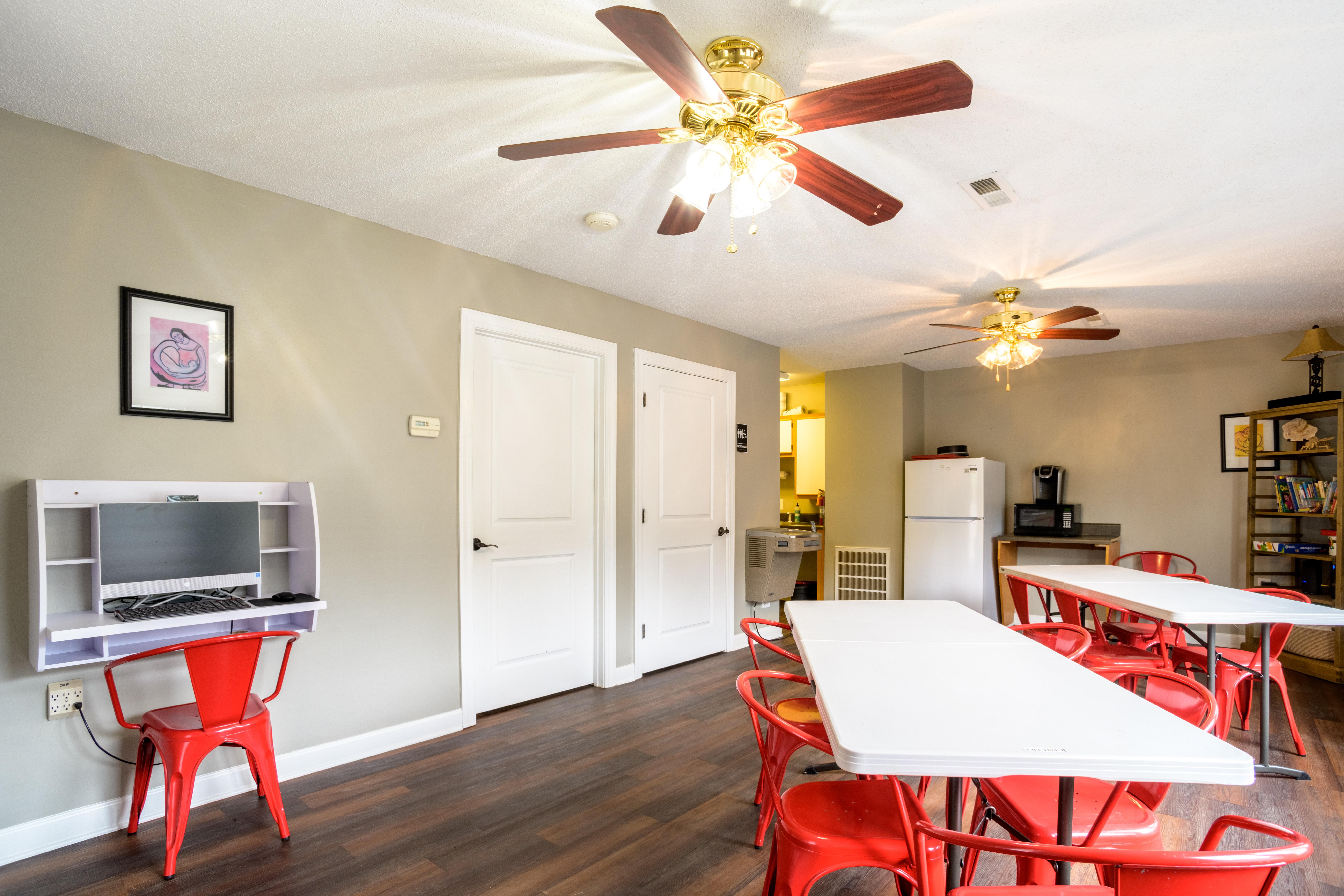A room with a white ceiling fan and a white dining table with red chairs.,A room with a white ceiling fan and a white dining table with red chairs.